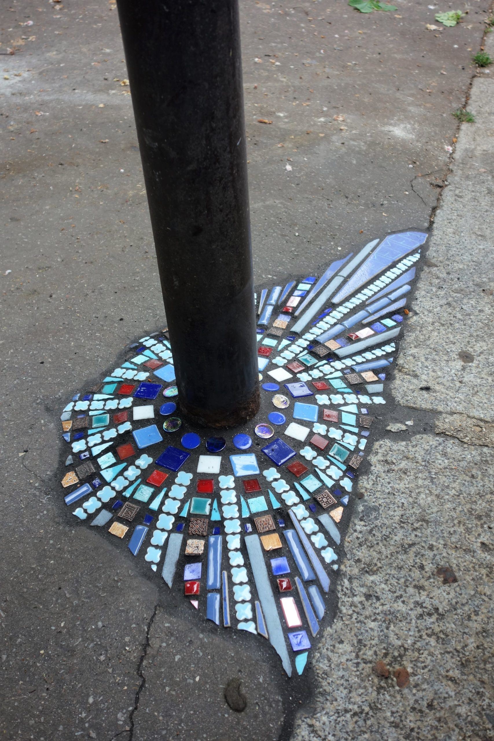 A photo of a colorful mosaic patching a concrete hole