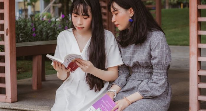 two light-skinned Asian women reading next to each other