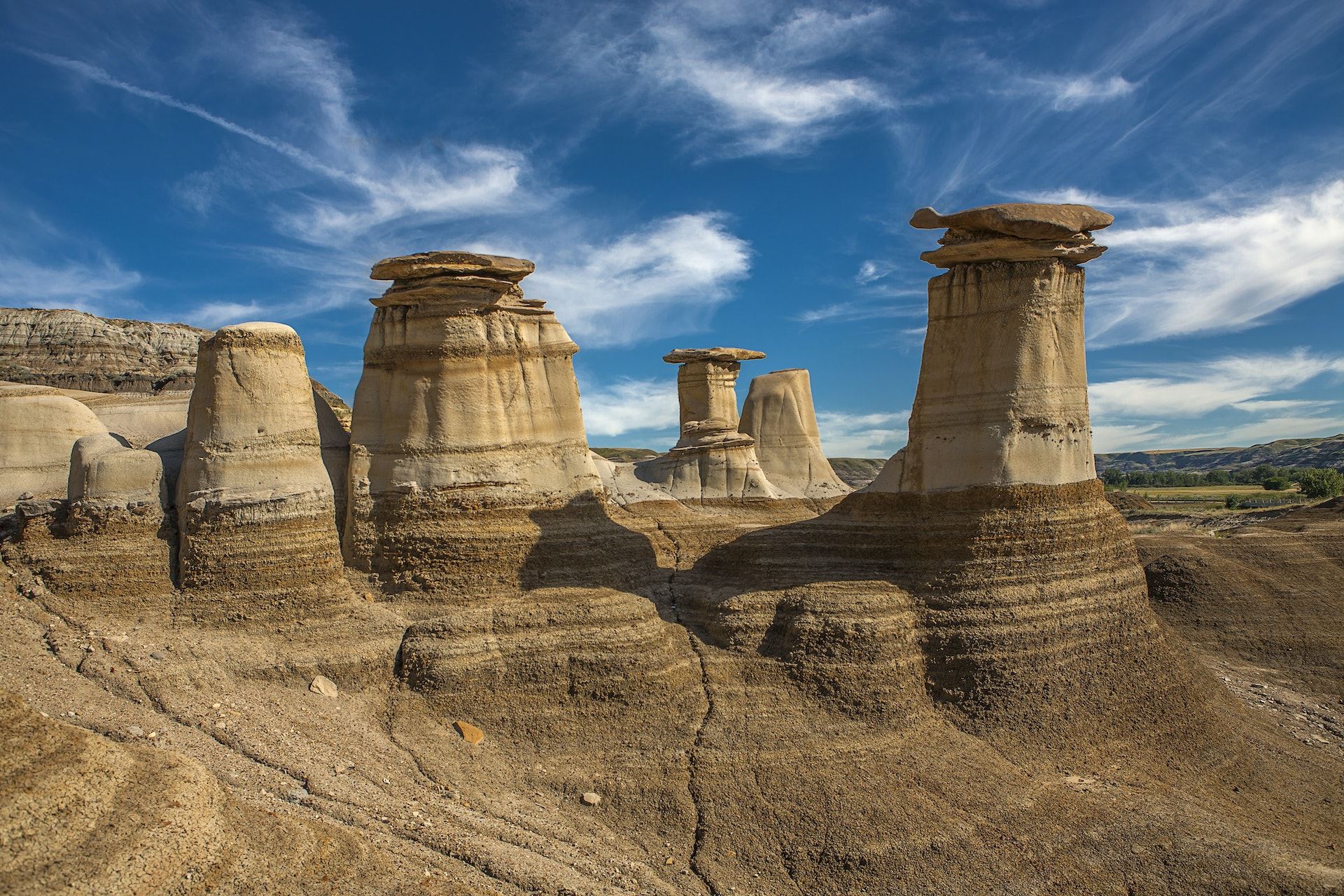 Geological wind-sculptured rock formations stand against a blue sky in the Drumheller badlands, Canada.