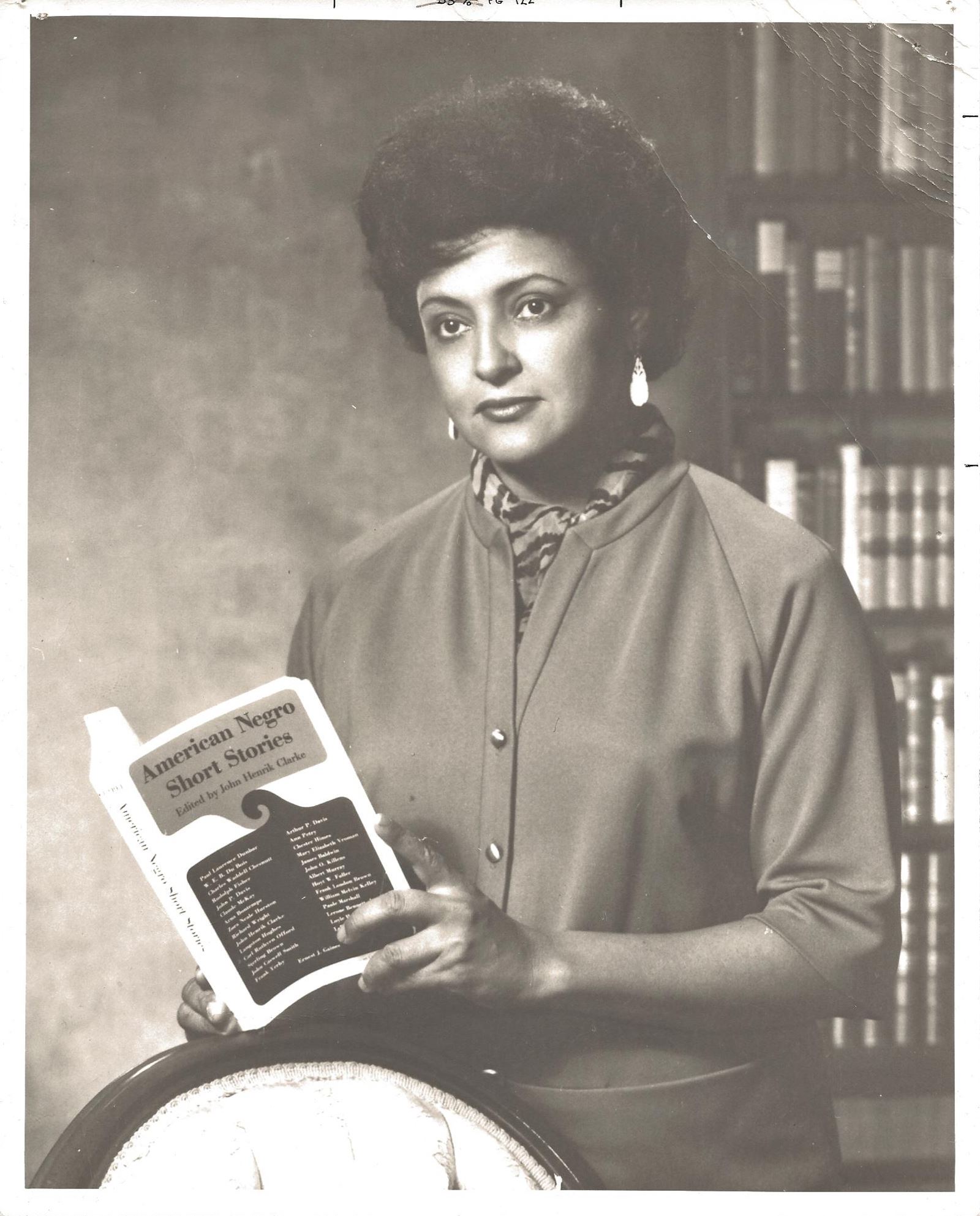 A black-and-white portrait of a woman holding a book titled 