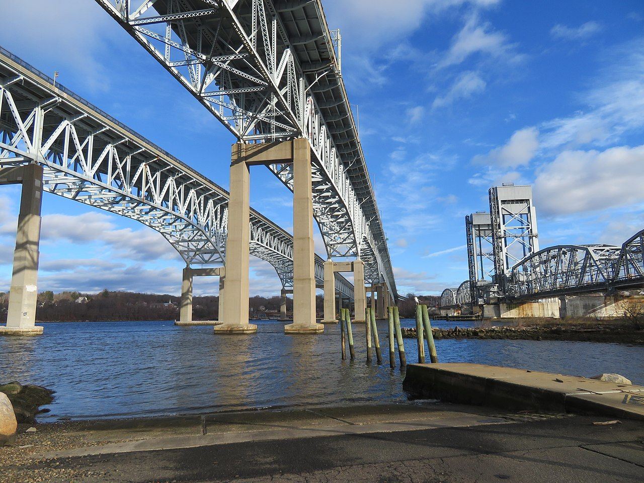 View from below of a twin silver bridges stretching across water.