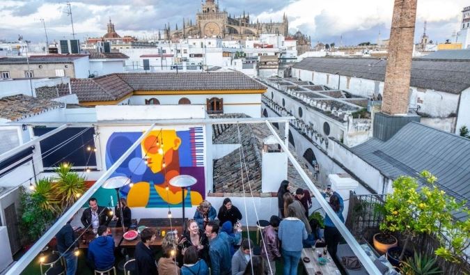 People partying on the rooftop of La Banda Rooftop Hostel with the skyline of Sevilla, Spain in the background